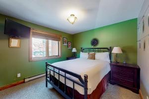 a bedroom with a bed with green walls and a window at Galena Street Getaway in Frisco