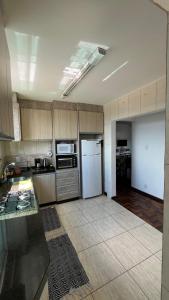 uma cozinha com armários de madeira e um frigorífico branco em Ap Central c/ Garagem em Ponta Grossa