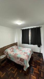 um pequeno quarto com uma cama e uma janela em Ap Central c/ Garagem em Ponta Grossa