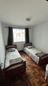 dwa łóżka w pokoju z oknem w obiekcie Ap Central c/ Garagem w mieście Ponta Grossa