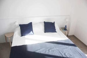 uma cama branca com almofadas azuis num quarto em OD'A Apartaments em Roses