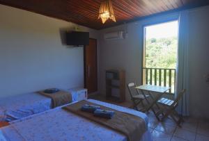 a bedroom with two beds and a table and a balcony at Serra Grisante Pousada Bed and Breakfast in Lençóis