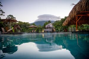 a swimming pool with a mountain in the background at Arenal Manoa Resort & Hot Springs in Fortuna