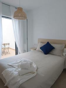 a white bed with white sheets and blue pillows at SHERRY SUÍTES III Apartamentos PARKING GRATUITO in Jerez de la Frontera