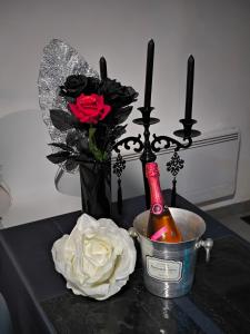 una mesa con una botella de champán y flores en Les Secrets d'Amandine en Troguéry