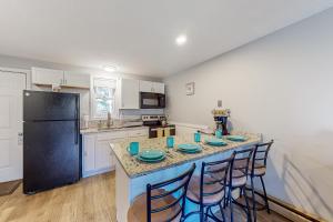 a kitchen with a counter with chairs and a refrigerator at Misty Harbor Beach Retreat in Gilford