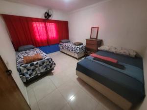 um quarto com 2 camas e uma janela com cortinas vermelhas em Casa Cmc011 Simples e Objetiva Com Estacionamento em Brasília