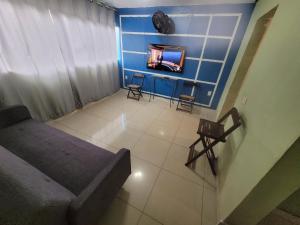 ein Wohnzimmer mit einem Sofa und einem TV an der Wand in der Unterkunft Casa Cmc011 Simples e Objetiva Com Estacionamento in Brasilia