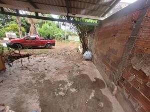 uma garagem com um carro vermelho estacionado ao lado de uma parede de tijolos em Casa Cmc011 Simples e Objetiva Com Estacionamento em Brasília