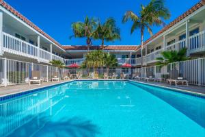 een zwembad tegenover een hotel met palmbomen bij Studio 6 Suites Carpinteria, CA Santa Barbara South in Carpinteria