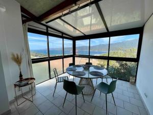 une table et des chaises dans une chambre avec une grande fenêtre dans l'établissement Charmante petite maison magnifique vue mer, à Propriano