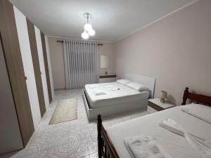 een witte slaapkamer met 2 bedden en een raam bij Home Shkodra Center in Shkodër