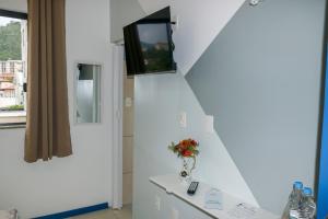 a room with a tv on a wall with a vase of flowers at Metro Hotel in Águas de Lindoia