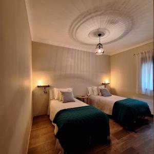 a bedroom with two beds with green sheets at Posada de la Clavería in Aldea del Rey