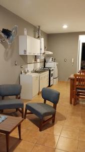 una cocina con armarios y sillas blancos y una mesa. en Departamento Amoblado Rio Cuarto 2 en Río Cuarto