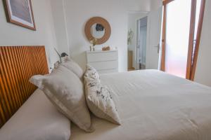 a bedroom with a white bed with pillows and a mirror at AROMA APARTAMENTO OLVERA in Olvera