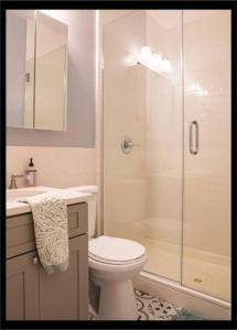 a white bathroom with a toilet and a shower at 3BR Central Park in New York