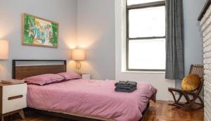 a bedroom with a pink bed and a chair and windows at 3BR Central Park in New York
