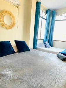 um quarto com uma cama com cortinas azuis e um espelho em Reef Hostel Manta em Manta
