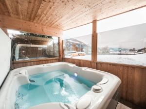 a jacuzzi tub in a room with a window at SportLodge GOLF SUITE - Cozy Apartment with Shared Pool, Whirlpool & Sauna, presented by AlpenLuxus in Kleinboden