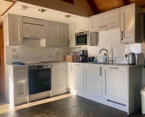 a white kitchen with white cabinets and a sink at Tigh Mairi at Mary's Thatched Cottages in Elgol