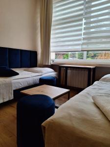 Cette chambre comprend deux lits et une fenêtre avec des stores. dans l'établissement Pokoje Gościnne Koral, à Miasteczko Śląskie