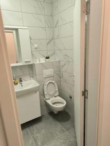 a white bathroom with a toilet and a sink at Apartman Kosmos in Banja Luka