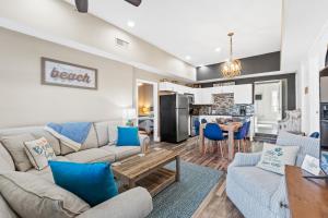 ein Wohnzimmer mit Sofas und einem Tisch sowie eine Küche in der Unterkunft Laguna Matata by Book That Condo in Panama City Beach