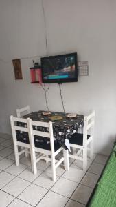 a table with two chairs and a television on a wall at Kitnet in Tramandaí