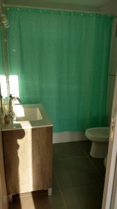 a bathroom with a sink and a green shower curtain at Casa Amoblada p/ Alquiler Temporario - Bahía Blanca in Bahía Blanca