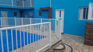 un edificio azul con una valla blanca y una puerta en Pousada Cantinho Azul, en Passo de Torres
