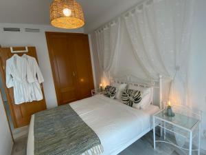 1 dormitorio con cama blanca y mesa de cristal en Casa del Sol en Calpe