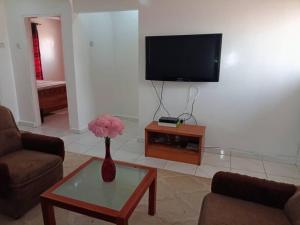 a living room with a vase with pink flowers on a table at Suleimane guest in Sere Kunda