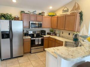 a kitchen with wooden cabinets and a stainless steel refrigerator at Destin Miramar Walk To Beach Pet Friendly in Destin