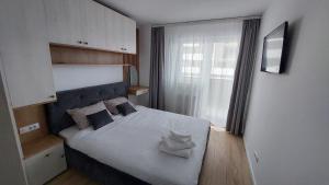 una camera da letto con un letto bianco con una finestra di Brasov Noua Holiday Apartament a Braşov