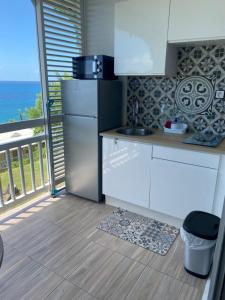 a kitchen with a refrigerator and a balcony with the ocean at MY Studio vue mer in Le Diamant