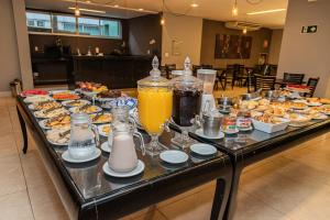 a buffet of breakfast foods and drinks on a table at Hotel Eldorado Flat in Contagem