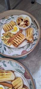 zwei Teller Essen auf einem Tisch mit Eiern und Toast in der Unterkunft The Edge Lodge in Polokwane