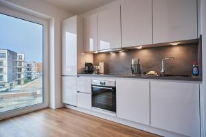 a kitchen with white cabinets and a large window at Schön Wohnen auf der Allerinsel in Celle