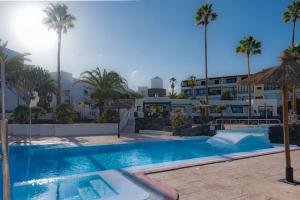 uma piscina com palmeiras e um edifício em Casa Junto al Mar em Costa Teguise