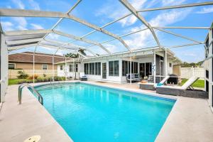 a swimming pool with a pergola next to a house at Beach Daze - Summer Sale! Southern Facing Pool, Walk To The Beach - No Ian Damage! in Naples