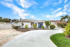 a white house with a fence and a driveway at Beach Daze - Summer Sale! Southern Facing Pool, Walk To The Beach - No Ian Damage! in Naples