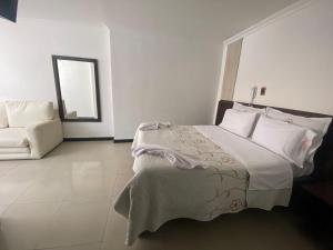 a white bedroom with a bed and a mirror at Hotel Yolima Real in Bogotá