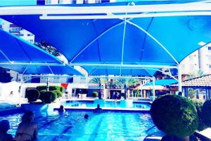 a swimming pool with blue umbrellas in a resort at Eldorado Thermas Park frente ao parque aquático in Caldas Novas