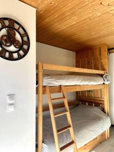 a bunk bed in a room with a clock on the wall at Appartement neuf à 400 m des remontées avec Sauna in La Chapelle-dʼAbondance