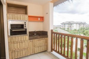 a kitchen with a balcony with a microwave and a sink at Praia do Cumbuco - Apartamento Completo - VG Sun in Caucaia