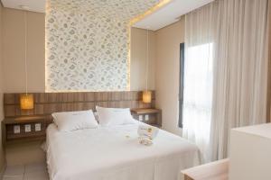 a bedroom with a white bed and a mirror at Praia do Cumbuco - Apartamento Completo - VG Sun in Caucaia