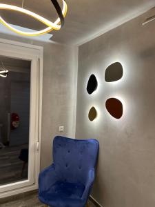 a blue chair in a room with a wall with holes at Overwave Apartment in Kavála