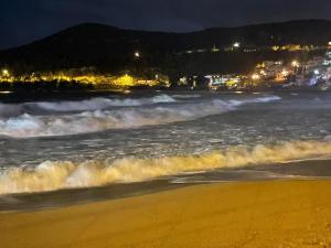 a beach at night with waves in the ocean at Overwave Apartment in Kavála