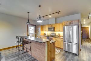 a kitchen with a stainless steel refrigerator and wooden cabinets at Downtown Columbia Falls Condo 16 Mi to Ski Resort in Columbia Falls